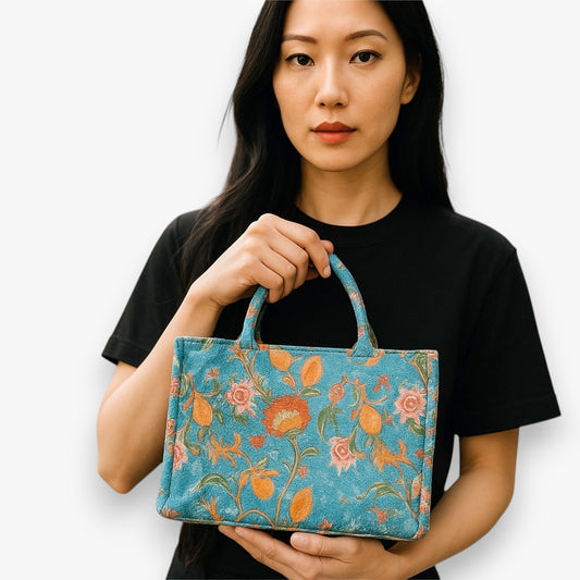 A woman holding a small blue tote bag with a vintage orange floral-patterned design.