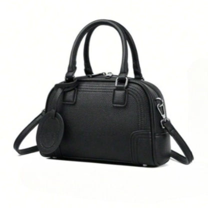 Celeste, a black PU leather handbag with top handles, silver hardware, and a detachable, adjustable crossbody strap attached.
