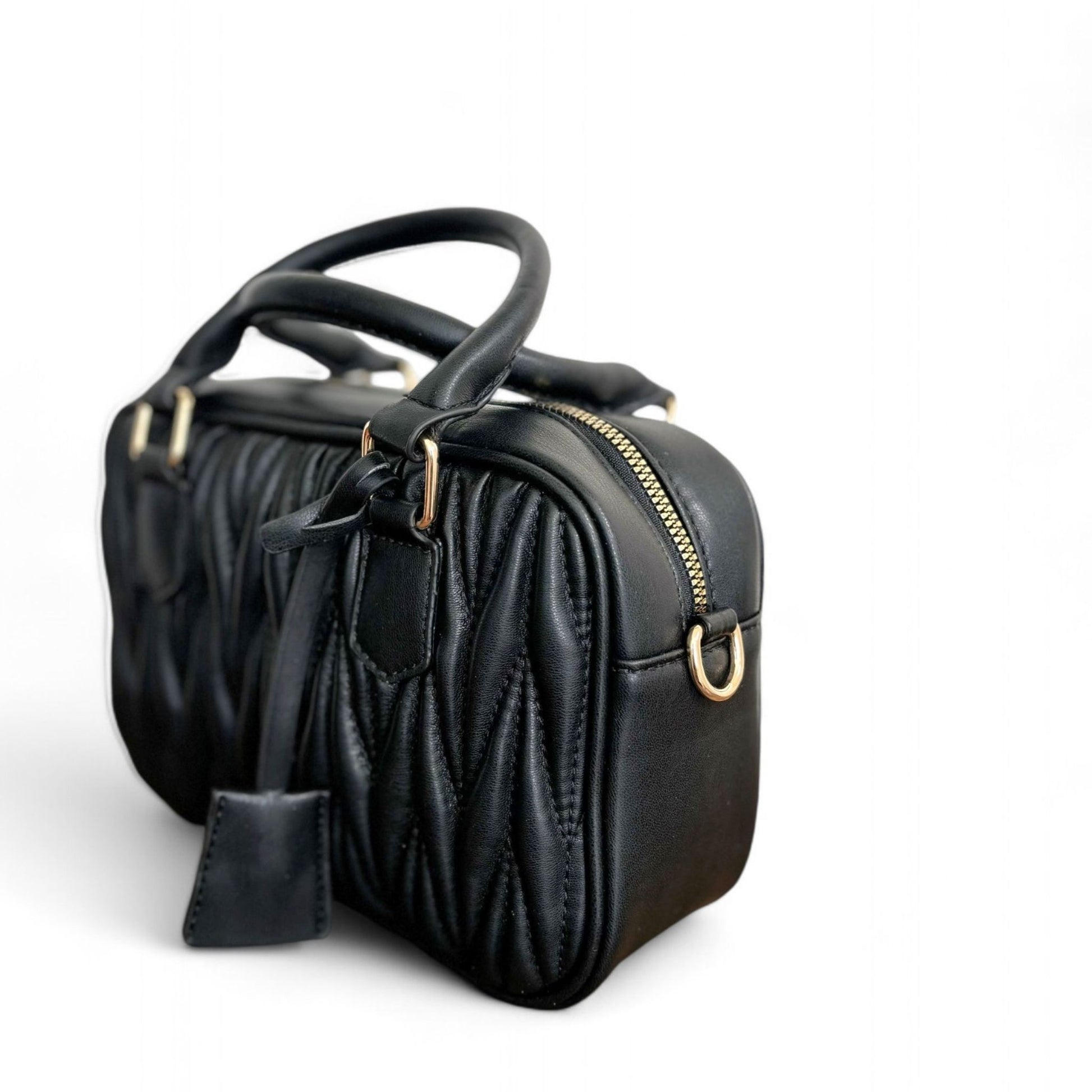 Angle view of black handbag with a quilted pattern, featuring gold-tone hardware and top handles. 