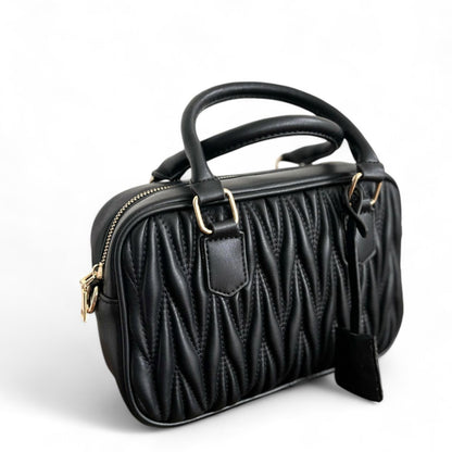 A black handbag with a quilted pattern, featuring gold-tone hardware & top handles.
