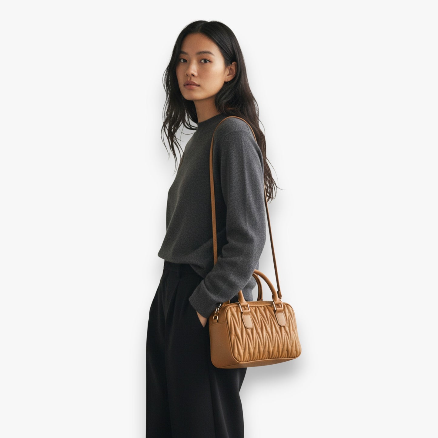 A model carrying a quilted shoulder bag with top handles and a long strap, ideal for elevating everyday style.