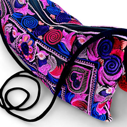 A close-up of a pink multi-coloured embroidered bag featuring intricate floral and bird patterns.