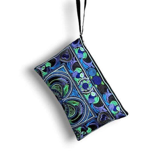 A rectangular embroidered blue and green wristlet bag with a floral and bird pattern and a strap.