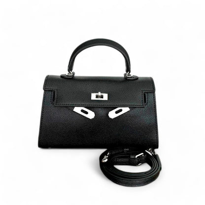 Black mini top-handle bag with silver hardware, closed flap & adjustable shoulder strap shown beside the bag.