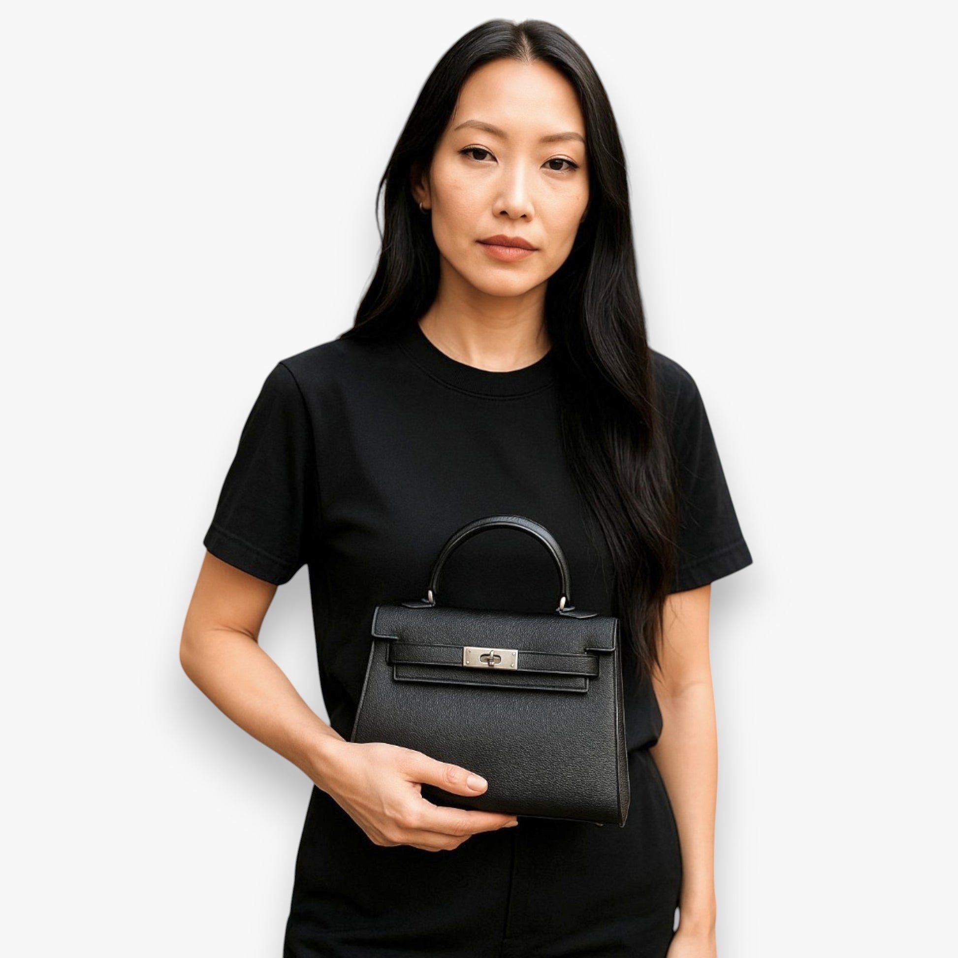 A woman carrying a timeless style mini top-handle bag in the palm of her hand.