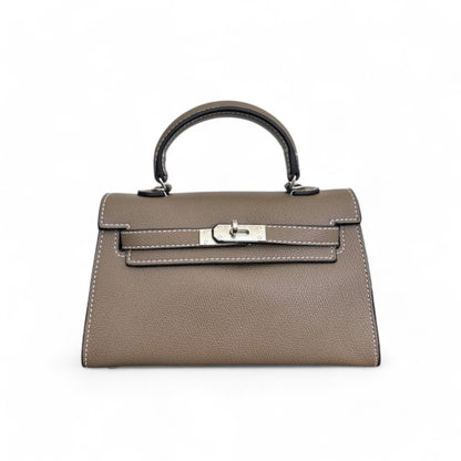 Front view of taupe mini top-handle bag with silver hardware & structured flap closure.