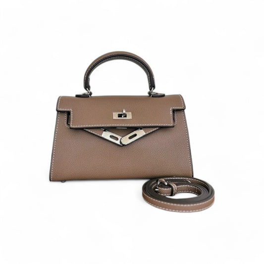 Taupe mini top-handle bag with silver hardware, flap closure & adjustable shoulder strap shown beside the bag.