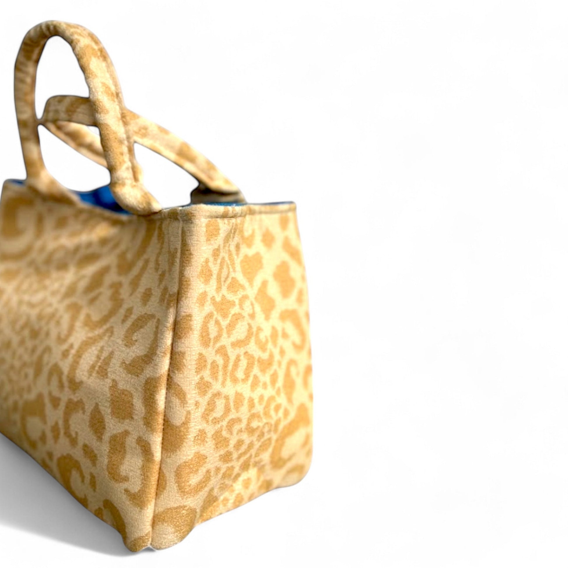 Side view of a handmade yellow leopard fabric mini tote bag with blue interior.