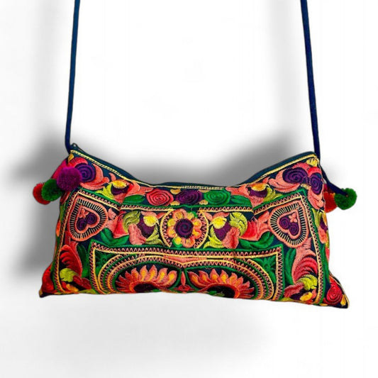 A vibrant orange bird and floral-patterned bag with mini pom-pom charms and a black cotton cord strap.