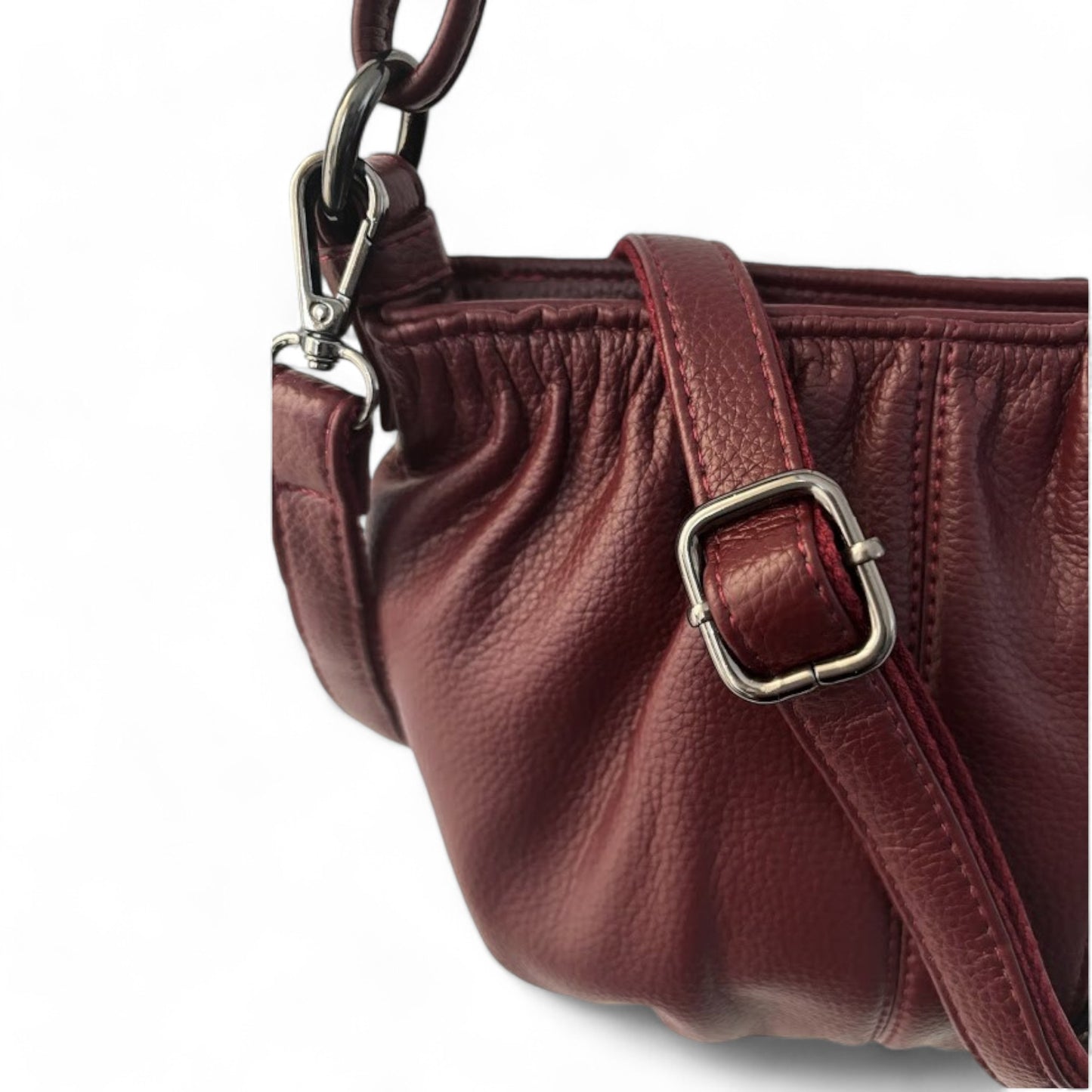 Close-up of a maroon pleated bag with a detachable shoulder strap and textured grain.
