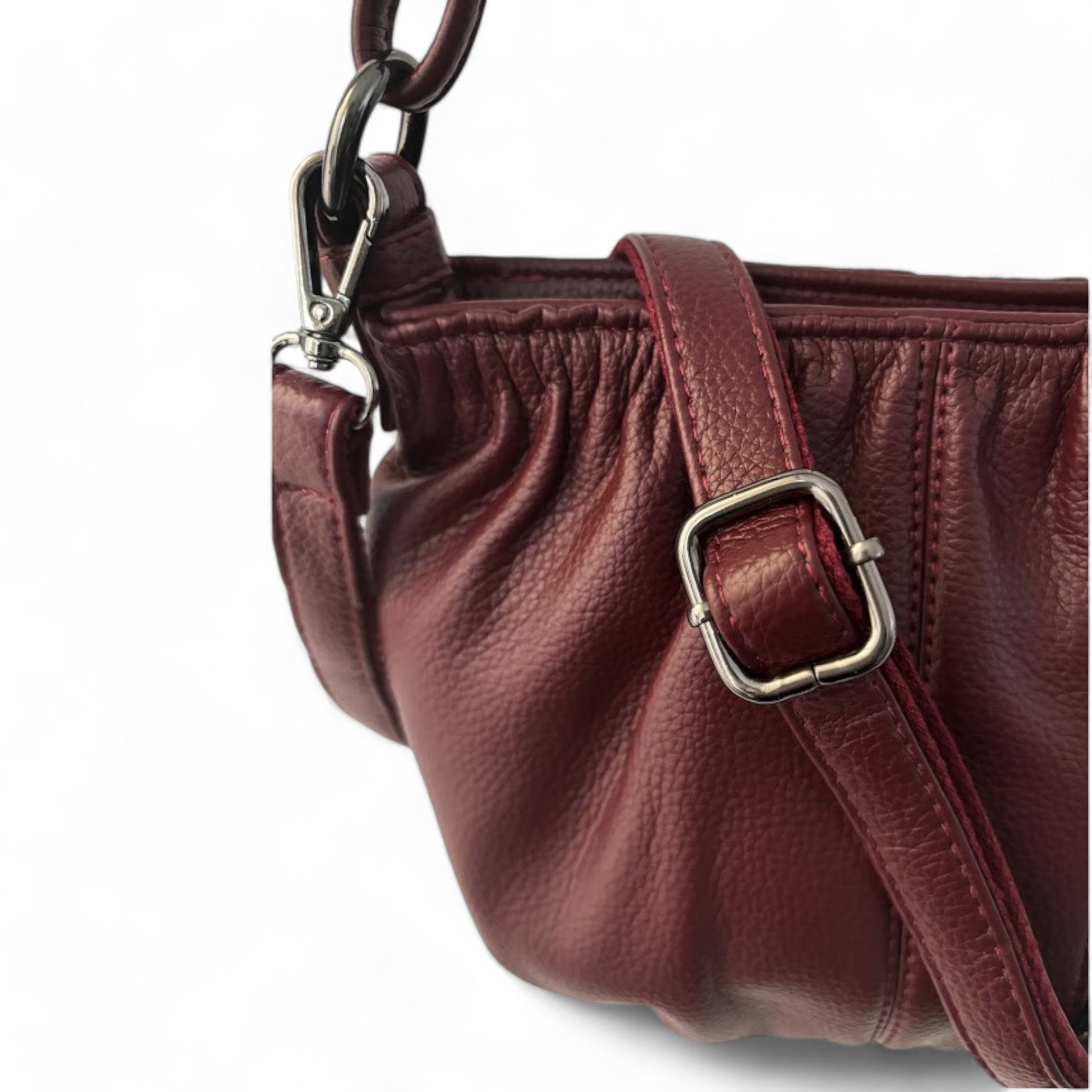 Close-up of a maroon pleated bag with a detachable shoulder strap and textured grain.