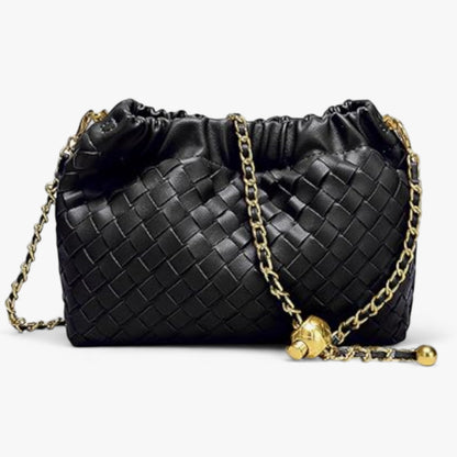 Close-up of a small hand-woven leather bag featuring a ruched top and gold chain shoulder strap.