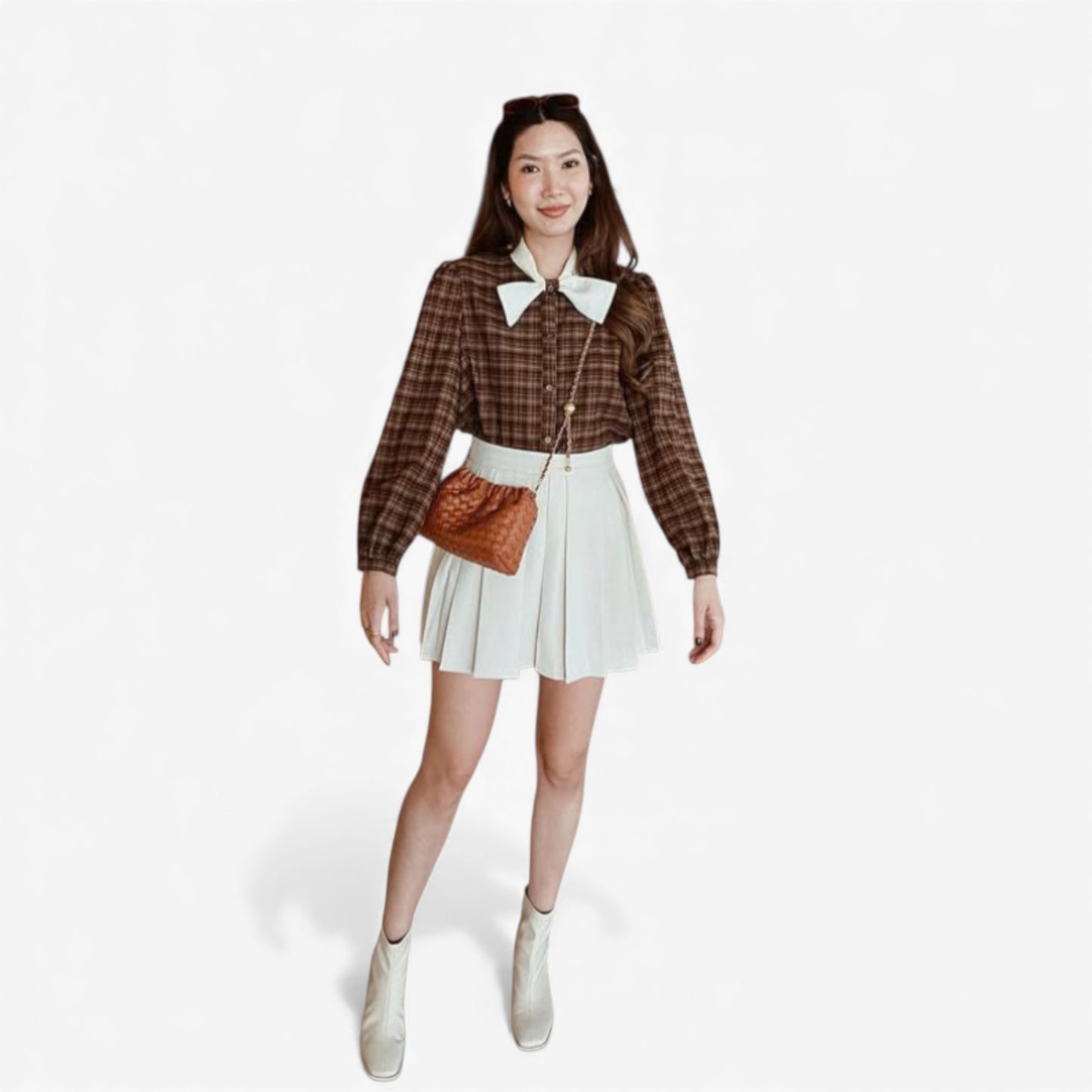 Full-body shot of a woman wearing a rusty brown weaving mini bag with a gold chain across her body.