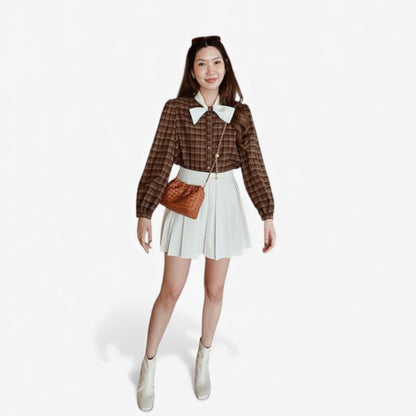 Full-body shot of a woman wearing a rusty brown weaving mini bag with a gold chain across her body.