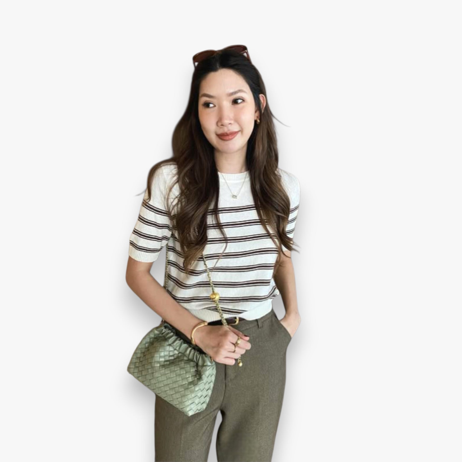 A woman worn a fashionable sage green hand-weaving bag with a gold chain on her shoulder.