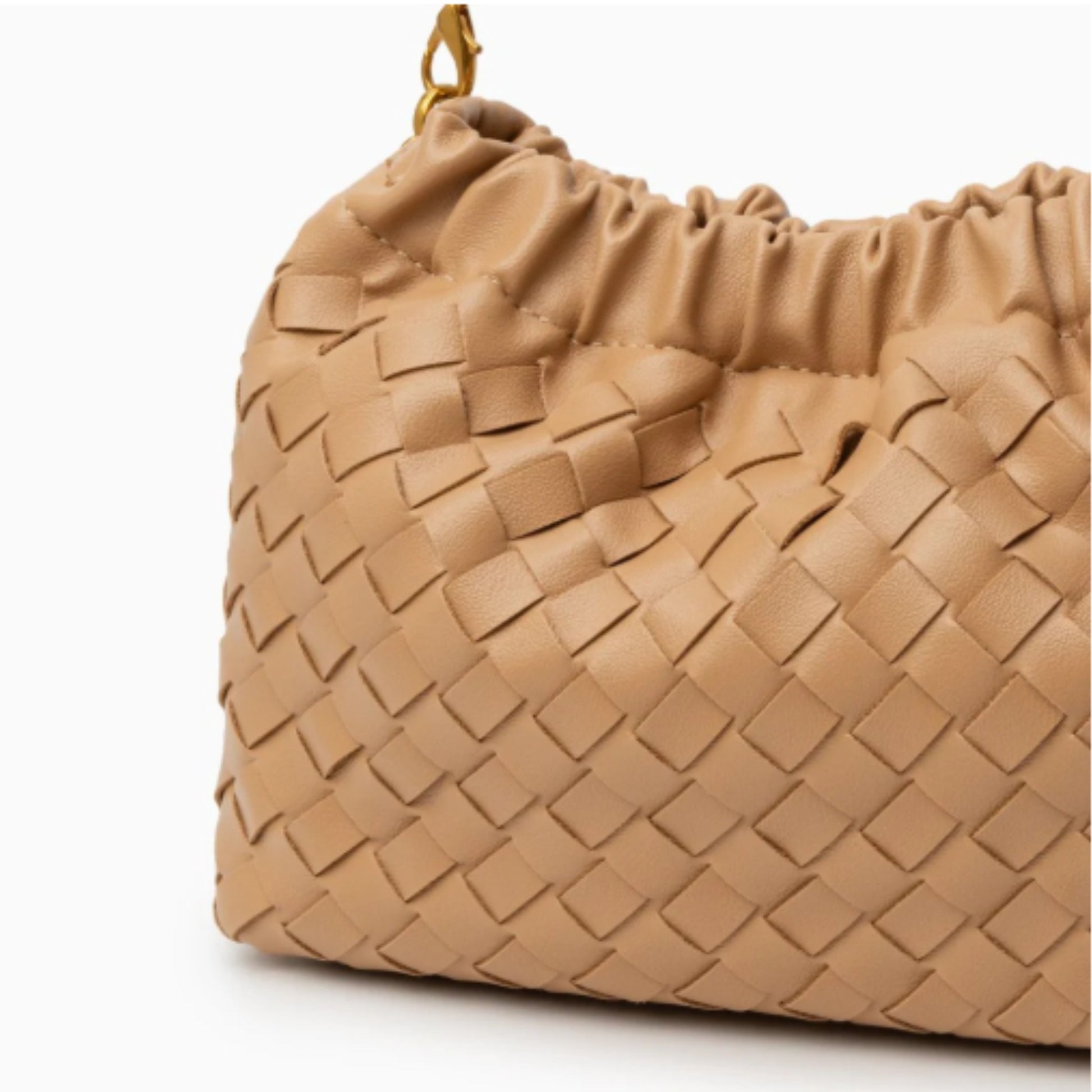 A close-up detail of a tan hand-woven vegan leather bag with a ruched top and a removable strap.