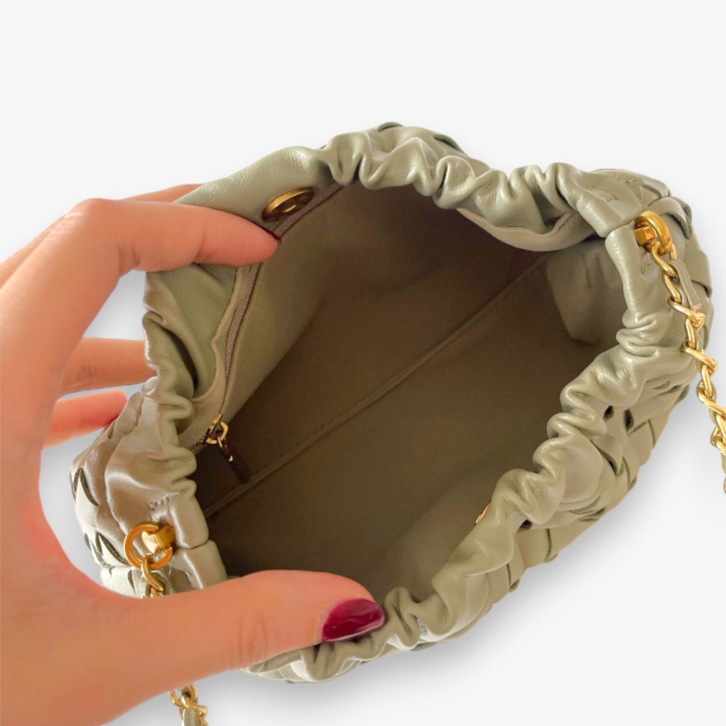 Open view of the sage green woven mini bag interior, showing the fabric lining and zippered pocket.