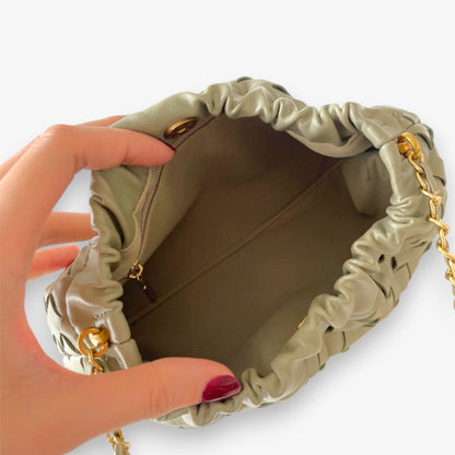 Open view of the sage green woven mini bag interior, showing the fabric lining and zippered pocket.