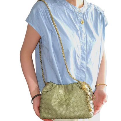 Woman carrying a green woven pattern bag with ruched tops and a gold chain strap on her shoulder.