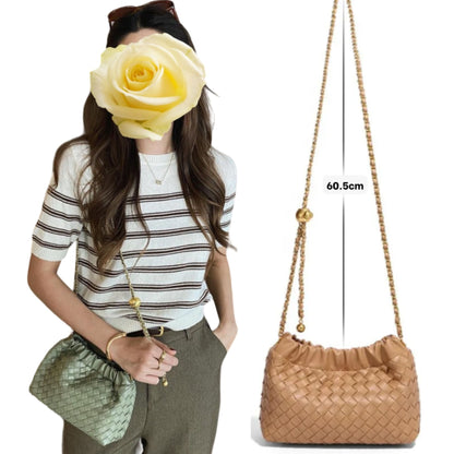 Woman wearing green woven bag with gold chain strap on her shoulder. Tan bag displaying beside her