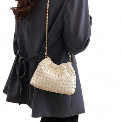 Side view of person carrying a white woven-patterned bag with ruched top and gold chain on her shoulder.