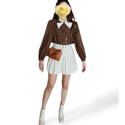 Women wearing a brown woven pattern bag with ruched top and gold chain across her body.