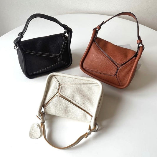 A collection of black, brown and white geometric bags with top handles.