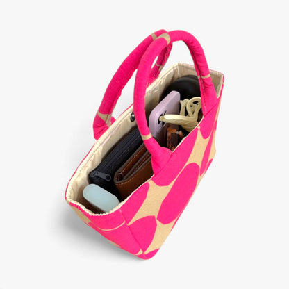 Top view of a small pink and beige tote bag showing essential everyday items.