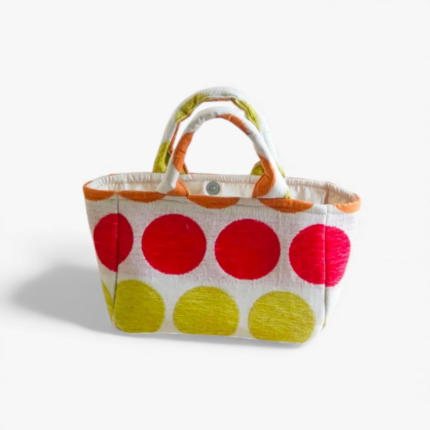 Orange, red and yellow polka dot bag with double handles and magnetic clasp.