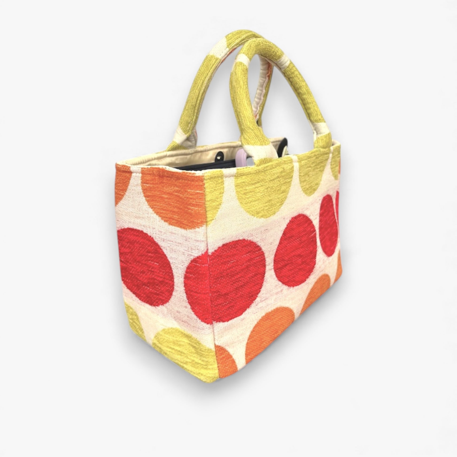 An angled view of a small handbag with a yellow, orange, and red polka dot pattern. 