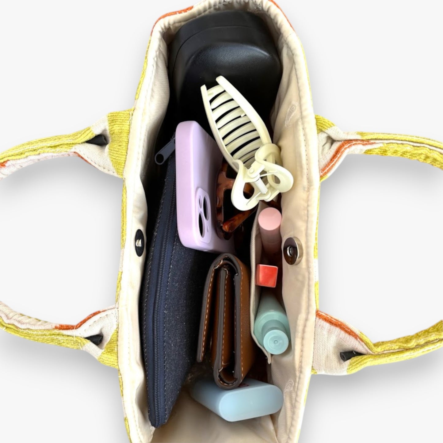 Top view of a small casual handbag with top handles showing everyday essential items.