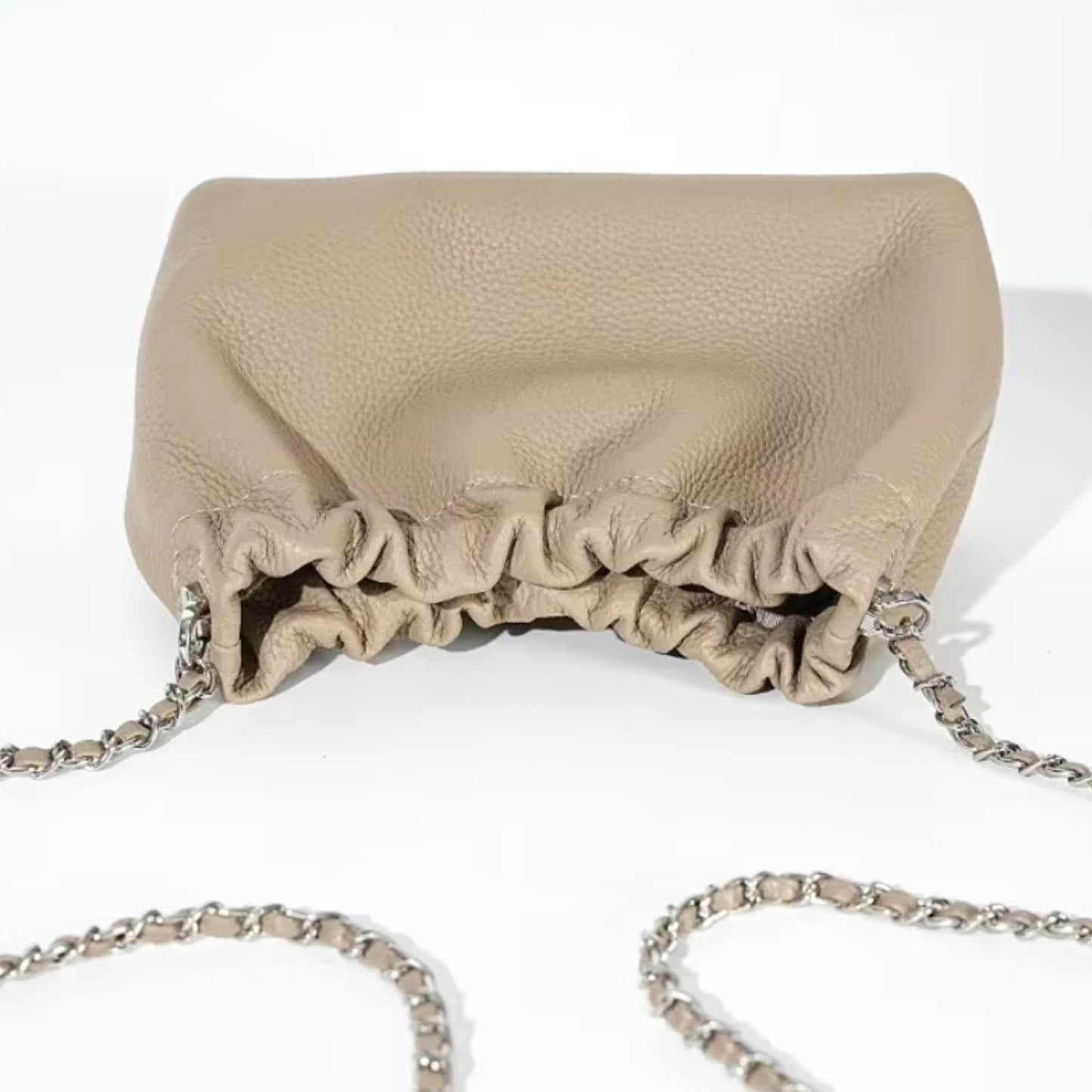 Close up of a beige pebbled leather handbag with a silver chain strap.