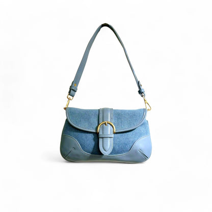 A blue denim shoulder bag with leather trim and a structured brass-tone buckle flap.