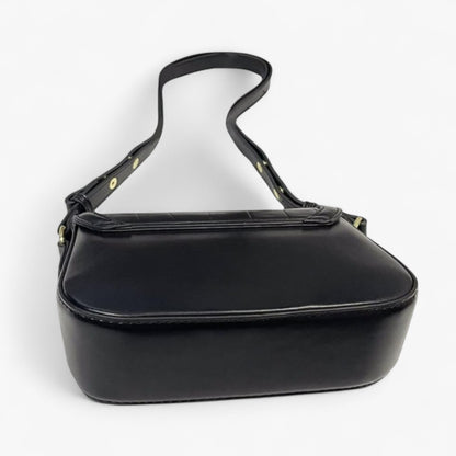 Rear view of a black handbag with gold accents, featuring a smooth back and base panel.