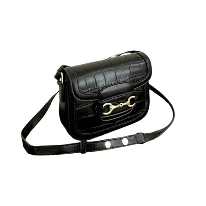Top front angle view of a black bag with a crocodile-embossed pattern, a gold horse bit, and a strap.