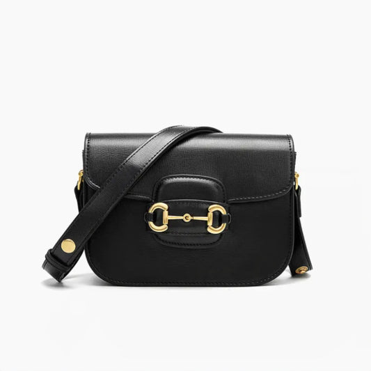 A black leather handbag with gold horse bit accents, with a front flap closure & a strap that goes across.