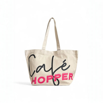 Large Café Hopper canvas tote bag with bold black and pink print, and long straps.
