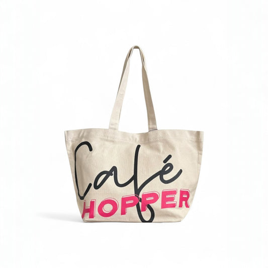 Large Café Hopper canvas tote bag with bold black and pink print, and long straps.