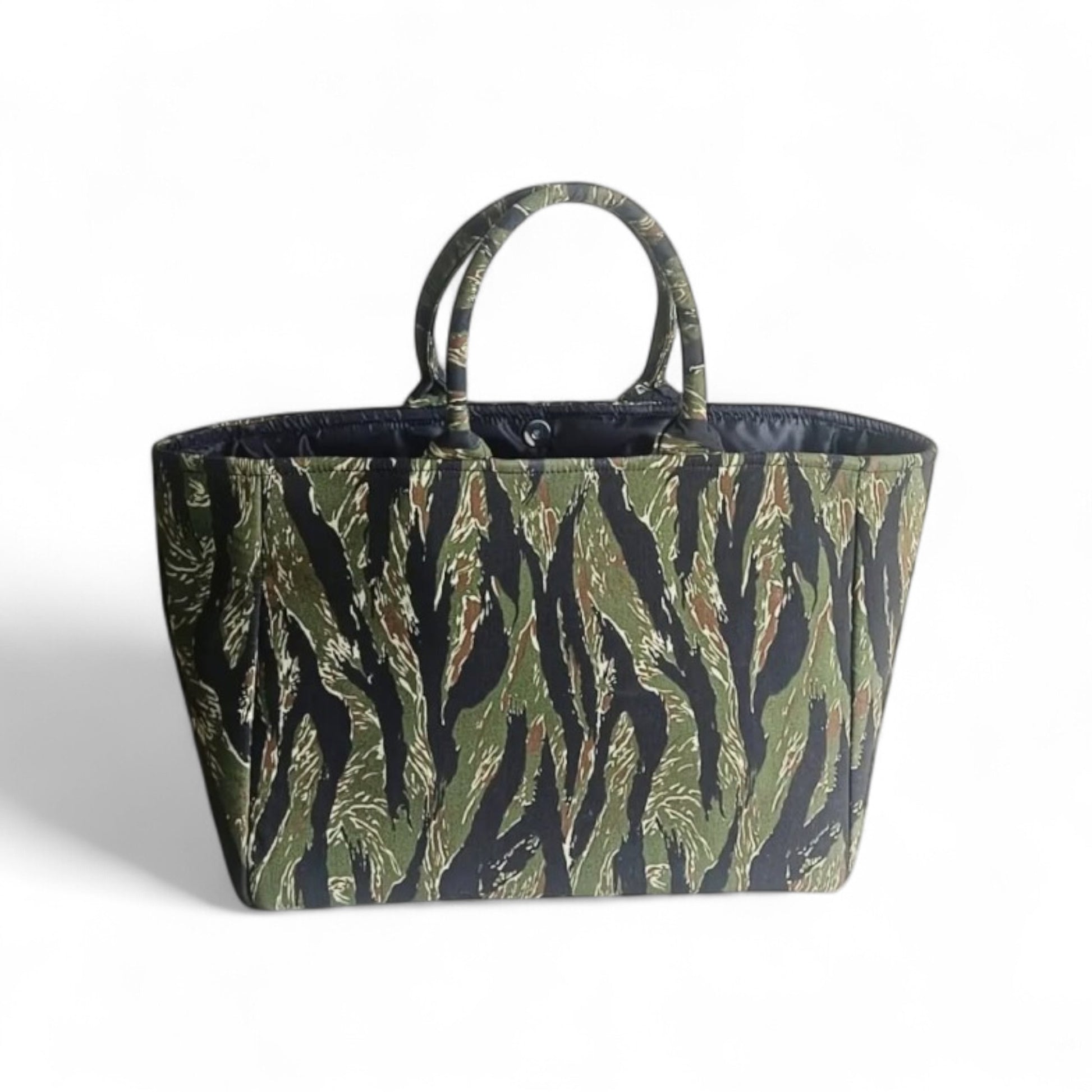 An open tote bag with a jungle green and black camouflage pattern, a magnetic closure and black lining.