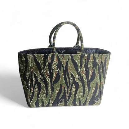 An open tote bag with a jungle green and black camouflage pattern, a magnetic closure and black lining.