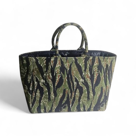 An open tote bag with a jungle green and black camouflage pattern, a magnetic closure and black lining.